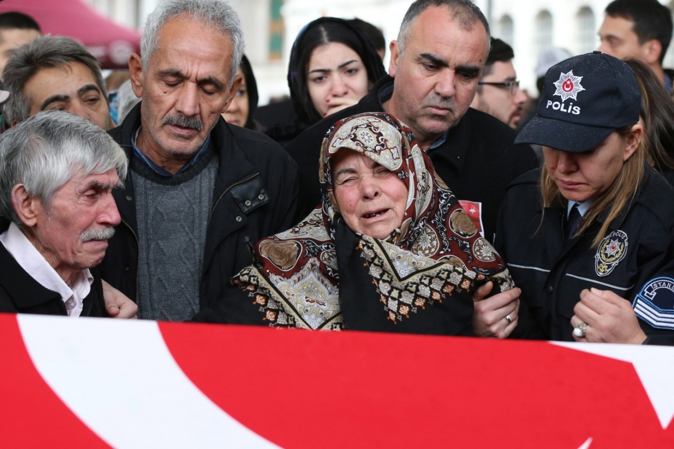 Relatives of police officer Hasim Usta mourn over his coffin during the funeral in Istanbul.