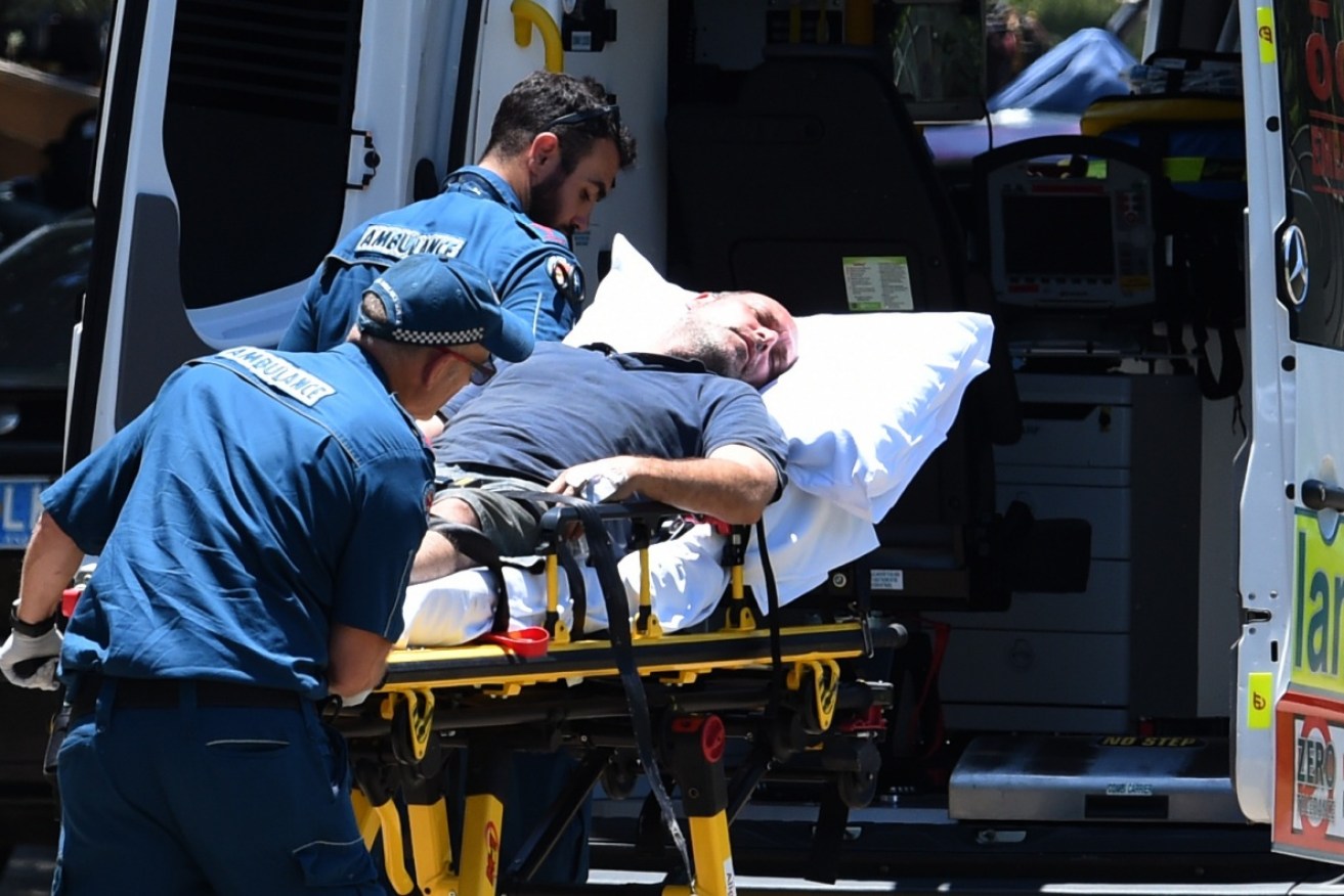 A man is taken away by paramedics from the scene of a fatal shooting at Carrara on the Gold Coast.