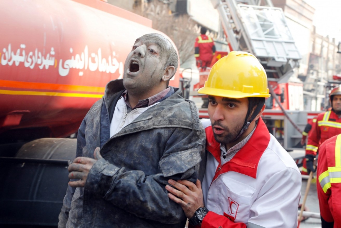 Rescue workers help an injured man at the scene of the Plasco building collapse. 