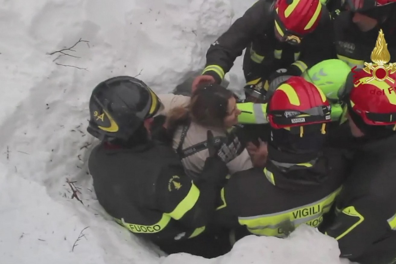 Firefighters rescue a woman alive from under snow and debris of an hotel that was hit by an avalanche in Rigopiano, central Italy,