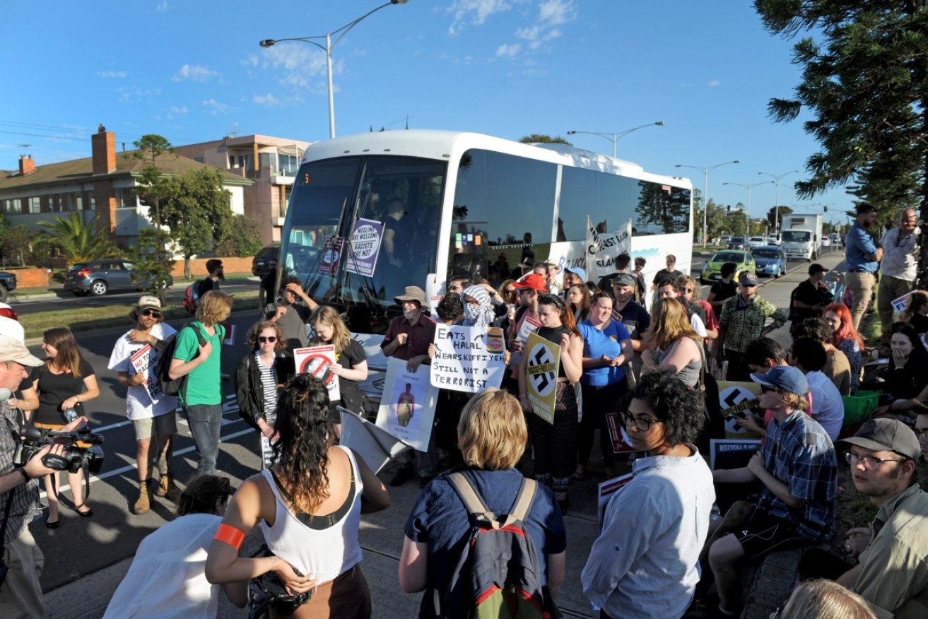 Protesters block a bus carrying Q Society supporters from leaving a pick up stop in Melbourne.