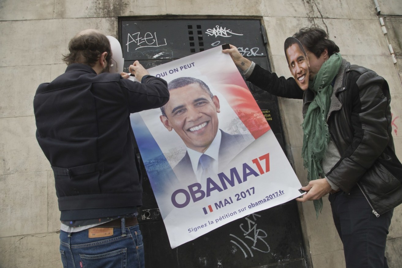 Two organisers of the online petition, wearing Barack Obama masks, stick up a campaign poster that reads "yes we can" in French. 