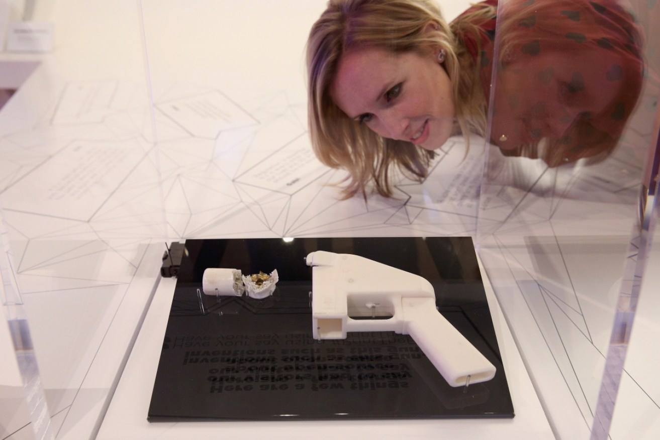 A woman inspects a 3D printed handgun.