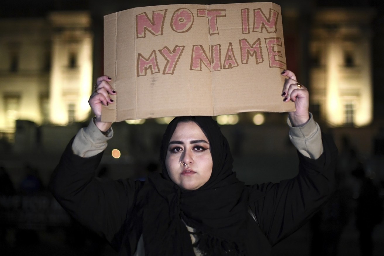 A woman holds a placard up during a candlelit vigil at Trafalgar Square .