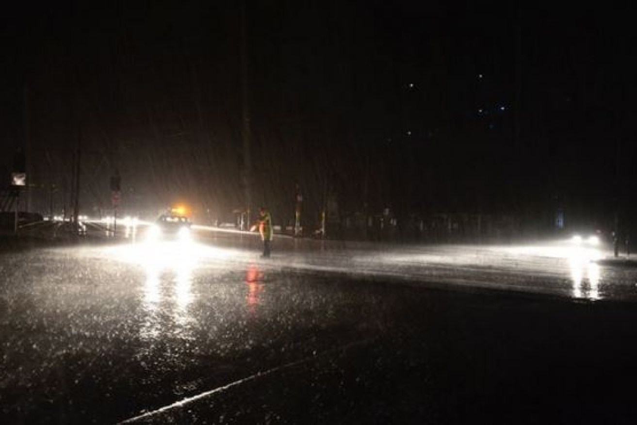 A lone policeman endures the dark and the driving rain to direct traffic with a flashlight during South Australia's September statewide blackout.September. 