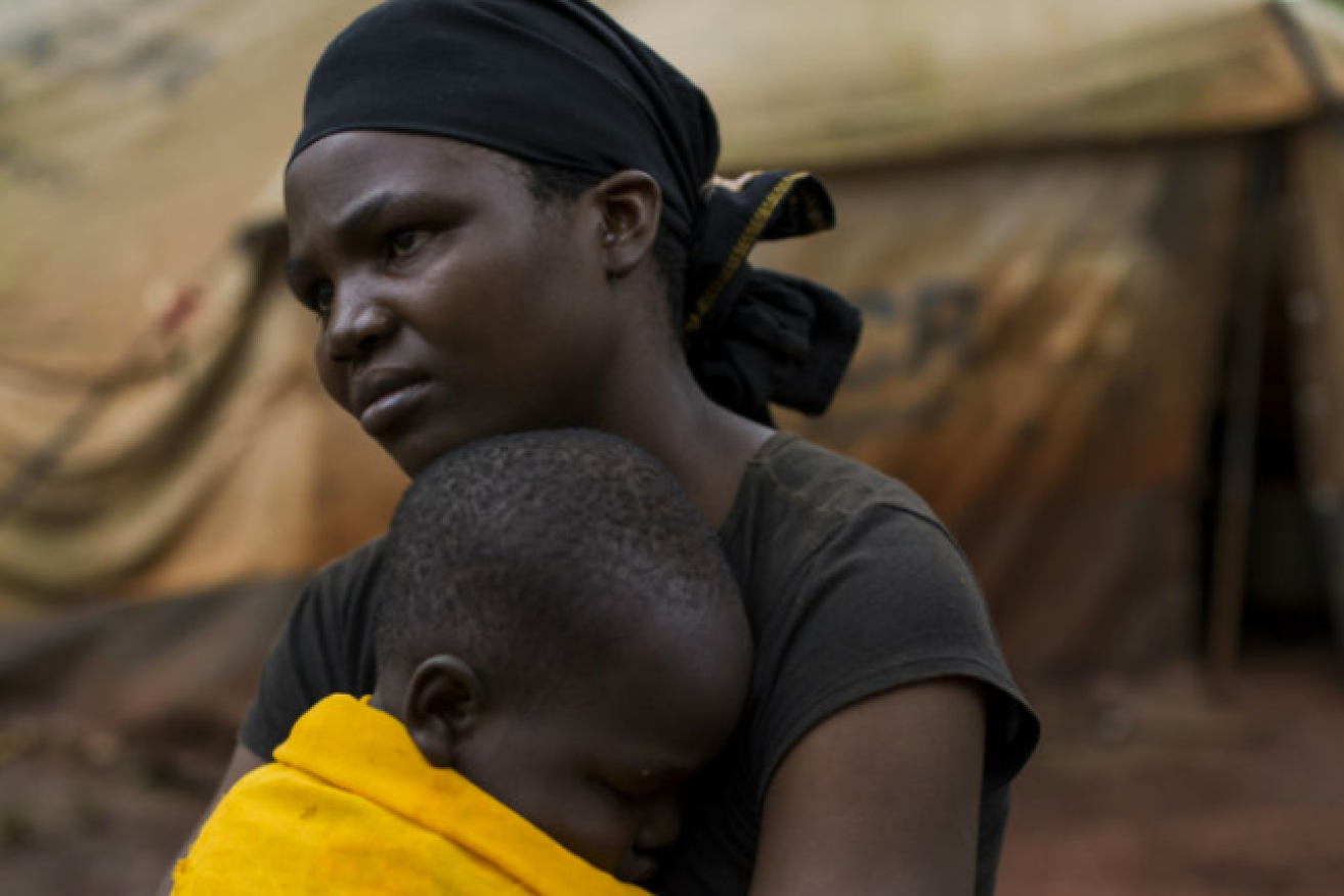 A female refugee sits with her youngest daughter outside her tent in the Nyarugusu refugee camp. 