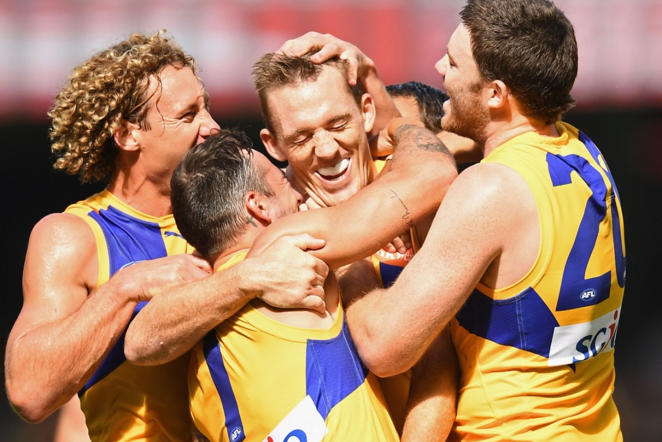 Former Kangaroo Drew Petrie is mobbed by Eagles teammates after kicking his first goal for his new club.