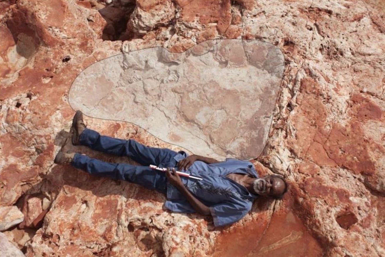 Richard Hunter lies next to a 1.7m dinosaur footprint belonging to a sauropod.