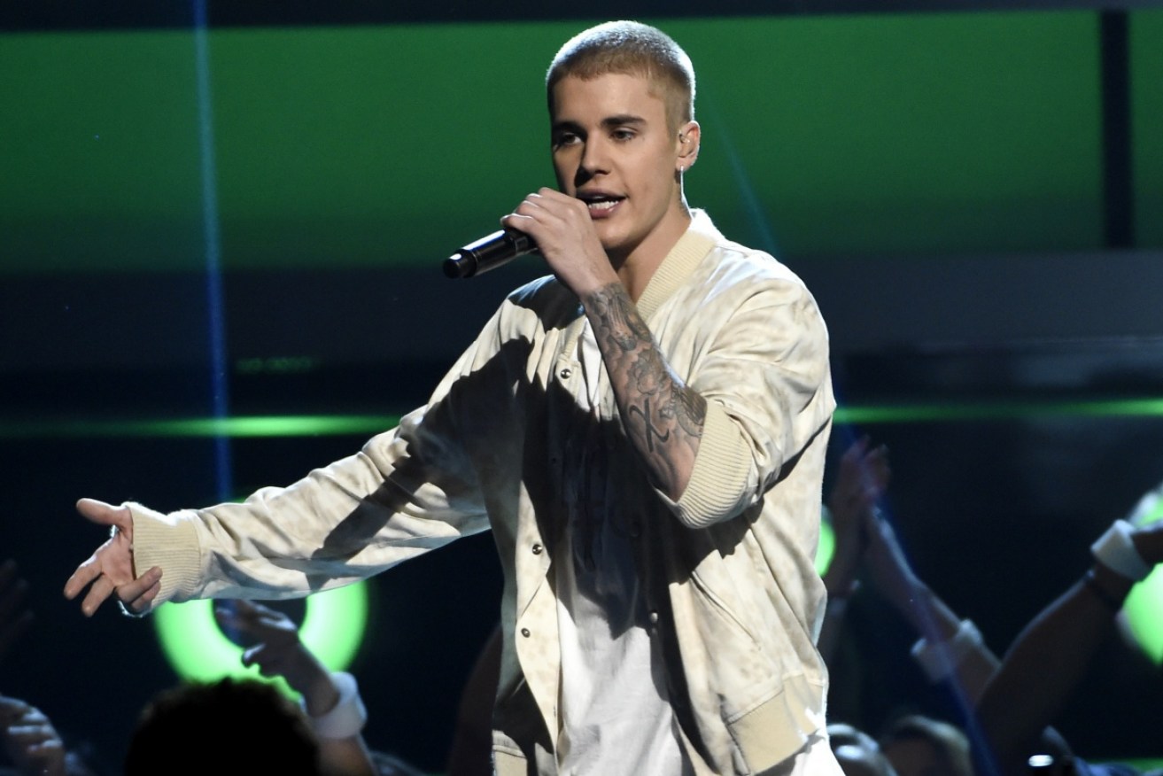 Justin Bieber shadowed by a swarm of obsessive fans.