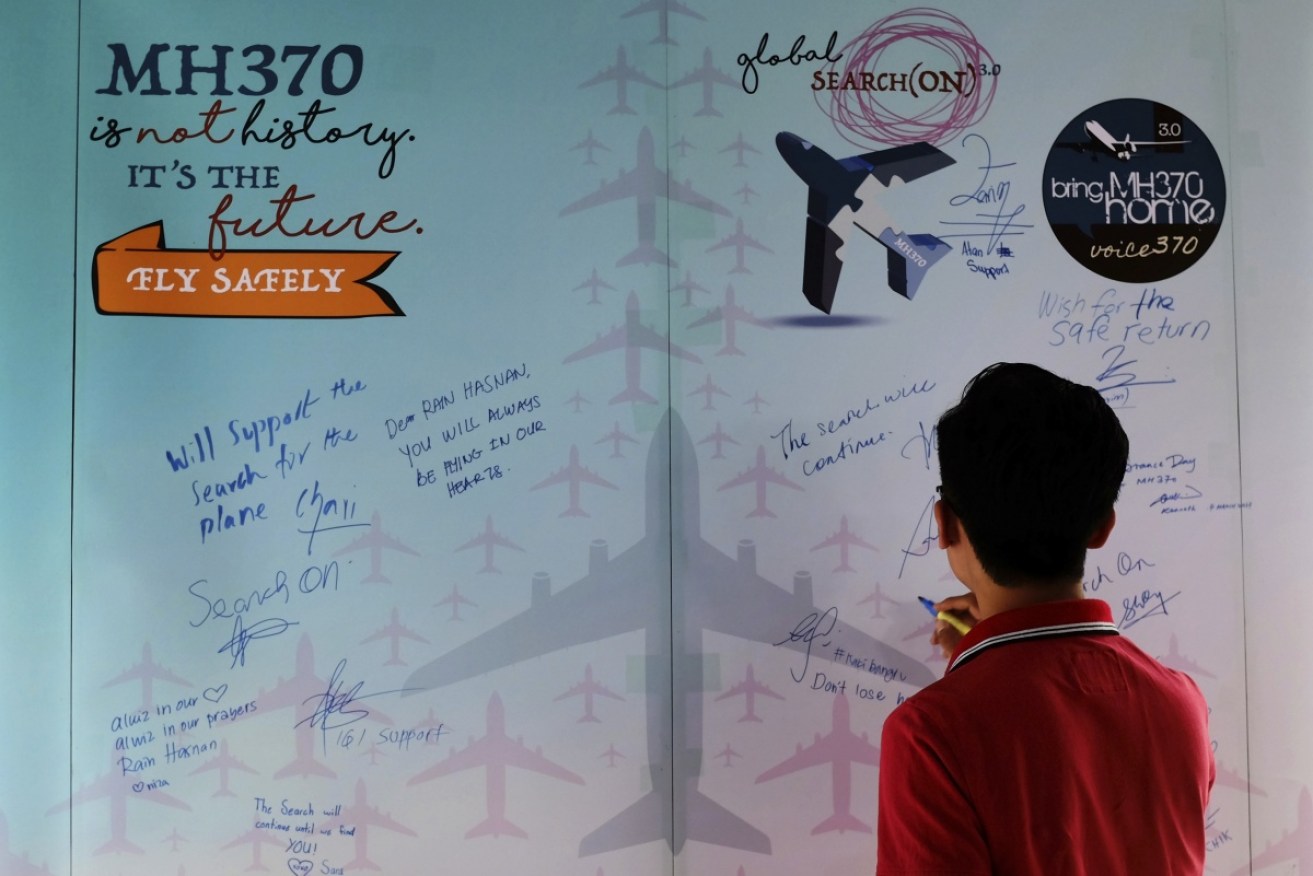 A man writes a condolence message during a Day of Remembrance for MH370 event in Kuala Lumpur.