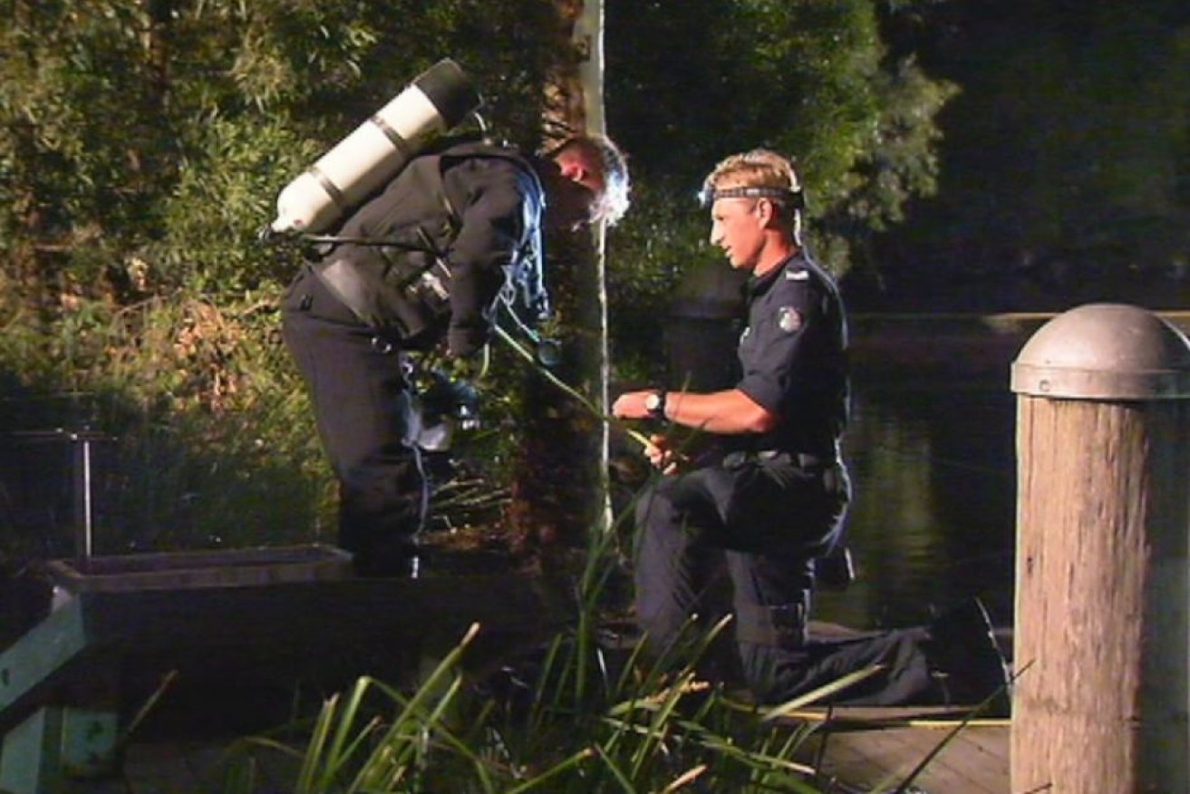 A police diver searches for the bodies of two men in a lake at Mill Park.