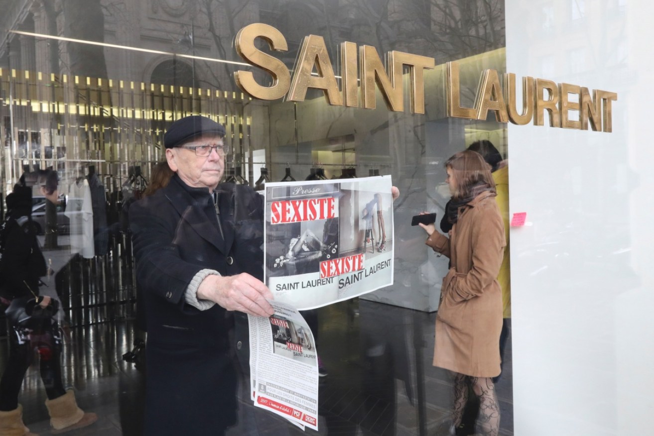A feminist activist protests in the window of a Saint Laurent store in Paris.