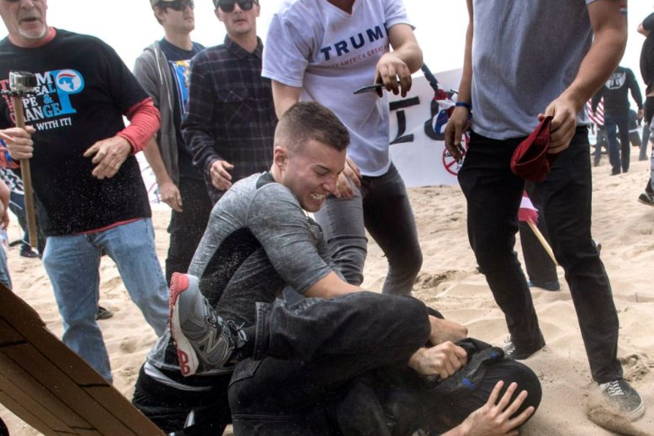 A Trump supporter beats an anti-Trump protester during wild scenes in Huntington Beach, Calif.