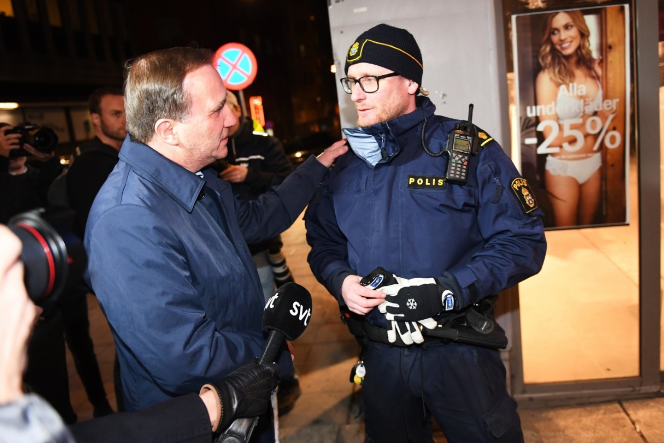Sweden's Prime Minister Stefan Lofven speaks to a police officer guarding Queens Street where a hijacked beer truck  drove into pedestrians at a central Stockholm department store.