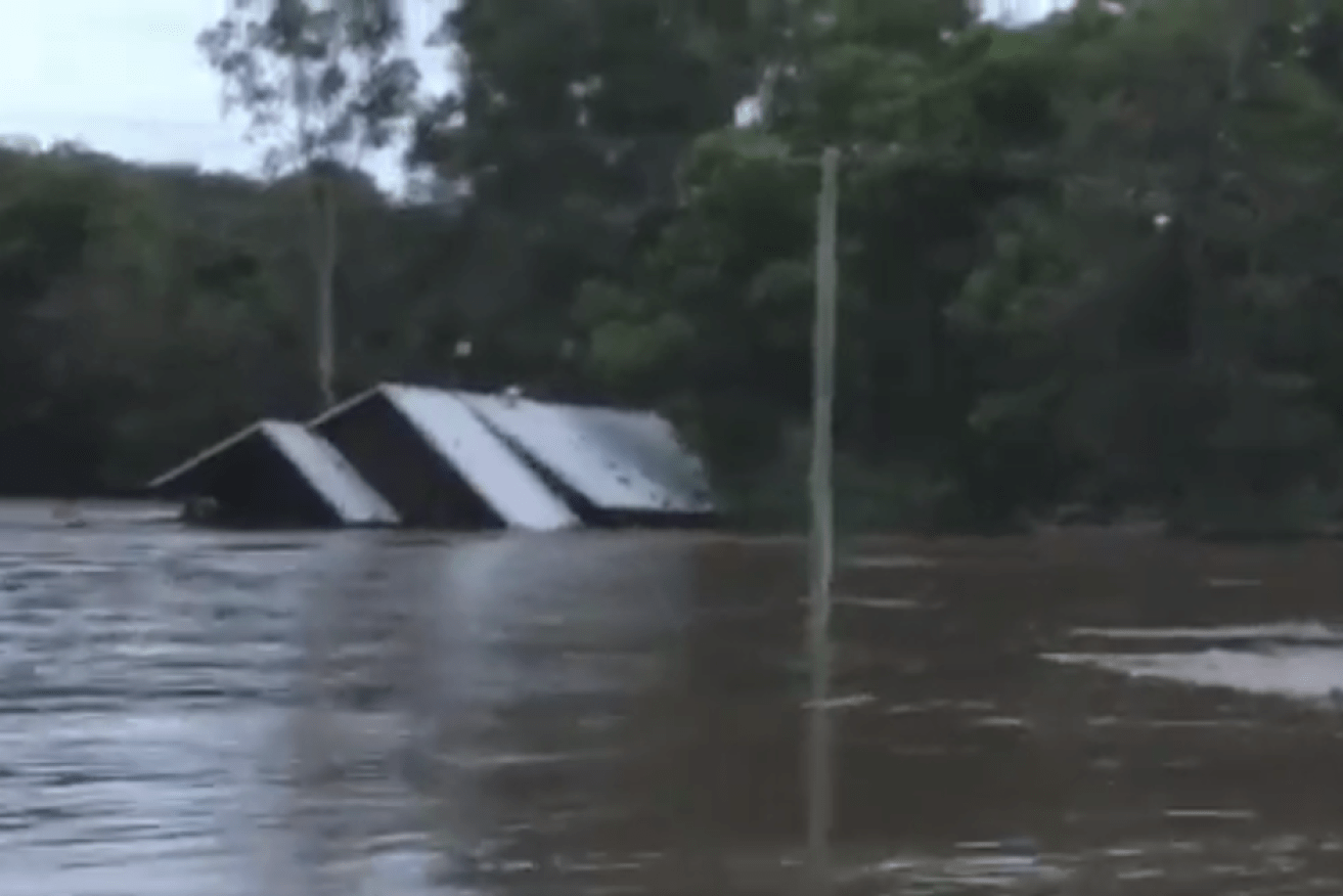 A house was swept away in floodwaters minutes after the family clinging to the roof were rescued.
