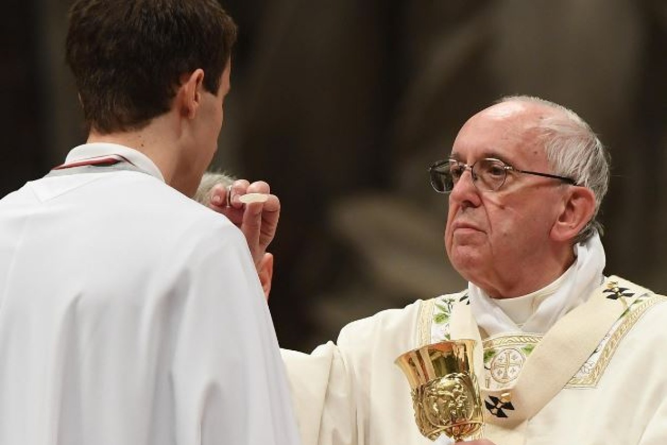 Pope Francis administers Holy Communion at Holy Saturday services in the Vatican.