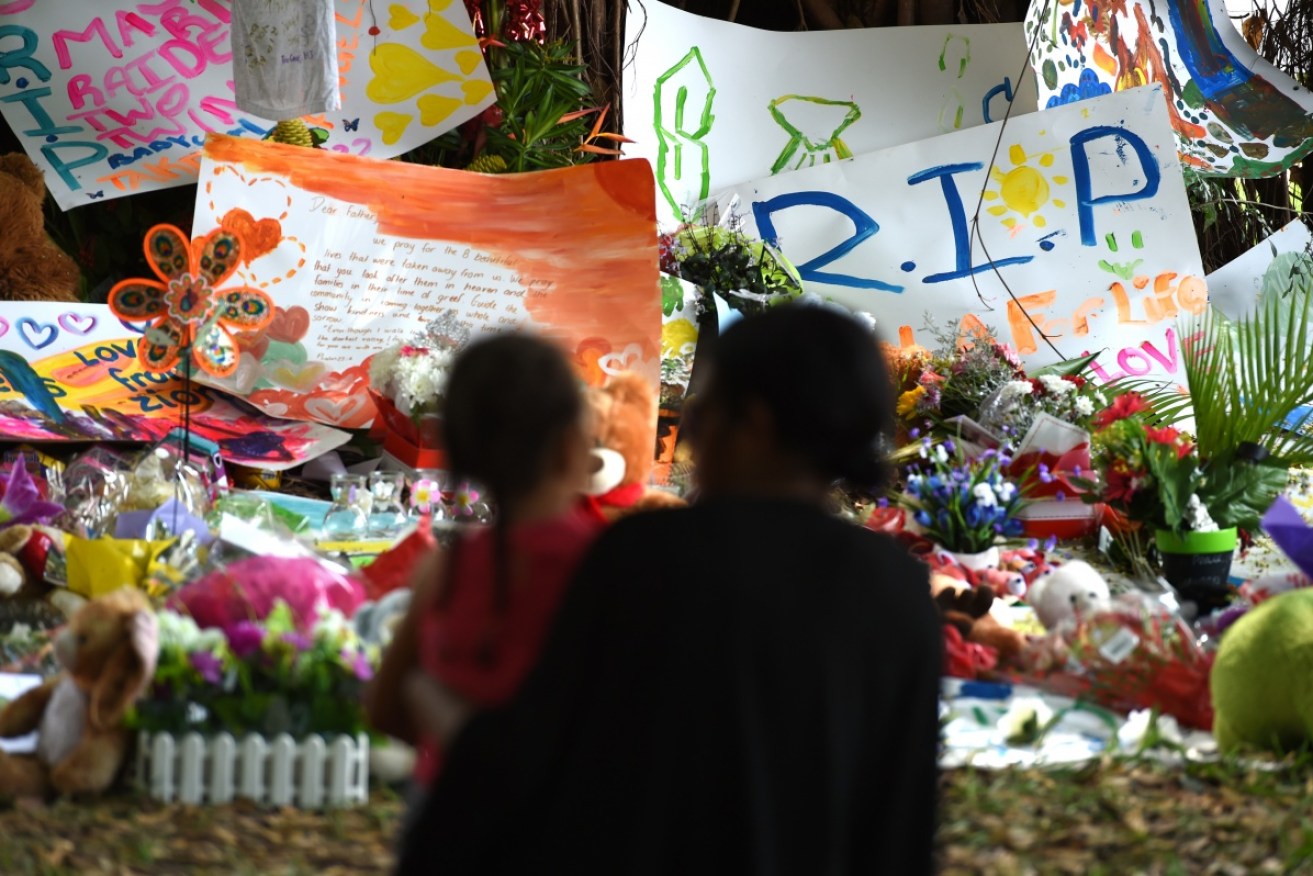 Mourners attend a floral tribute near the house where eight children were stabbed to death in Cairns, 2014.