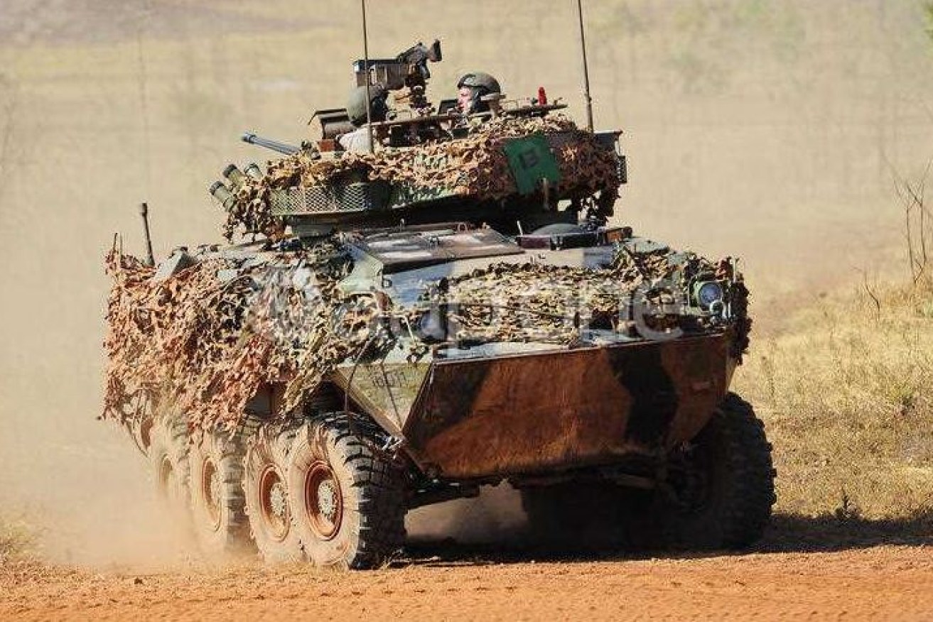 An Australian Light-Armoured Vehicle (ASLAV) raises dust at Mount Bundey, where a soldier has died of head wounds. 