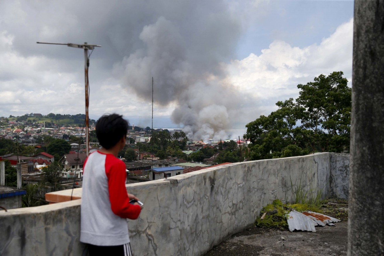 A resident watches the Philippine Air Force bomb militant positions.