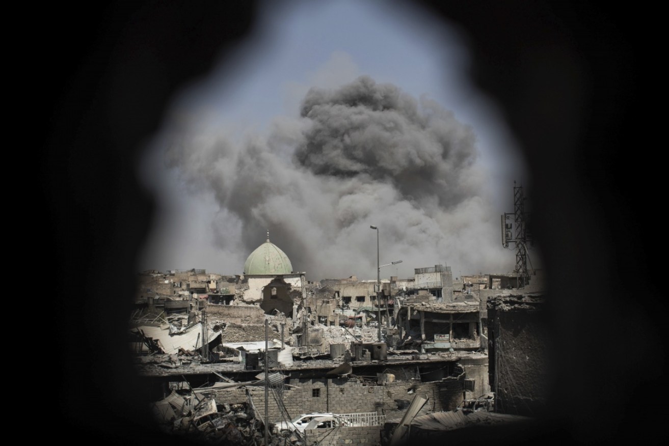 A bomb explodes behind the al-Nuri mosque complex, as seen through a hole in the wall of a house, as Iraqi Special Forces move toward Islamic State militant positions in Mosul on June 29, 2017.