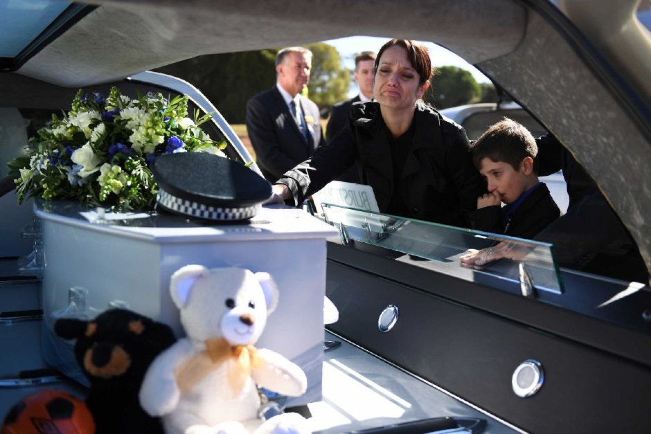 Senior Constable Forte's wife Susan and son Brodie touch the casket after his funeral service in Toowoomba.