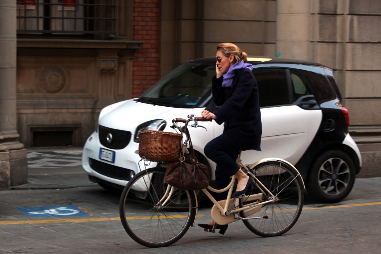 A woman talks on her mobile phone while cycling in Bologna, Italy