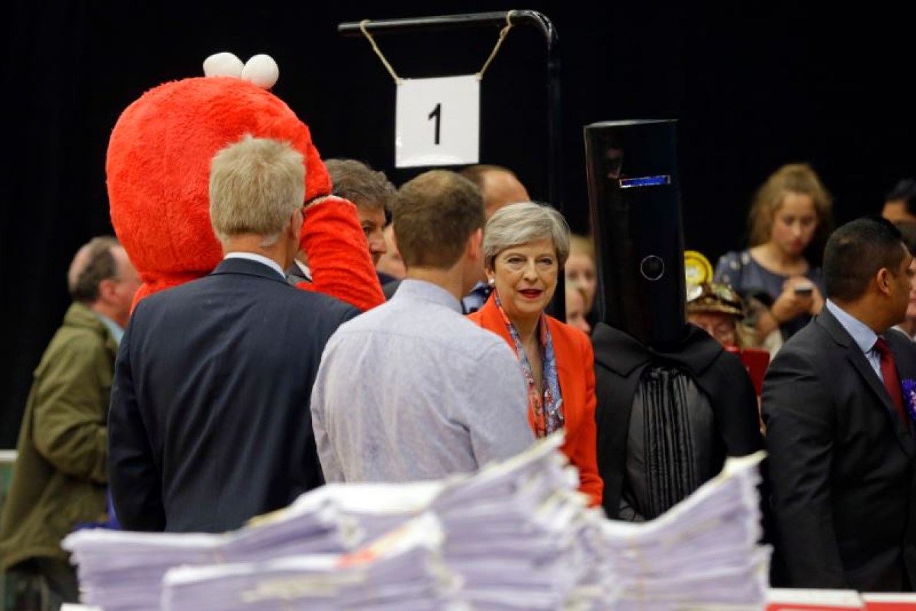 Who's the muppet? Theresa May awaits the tally with two of the joke candidates - Elmo and the black-clad Lord Buckethead.