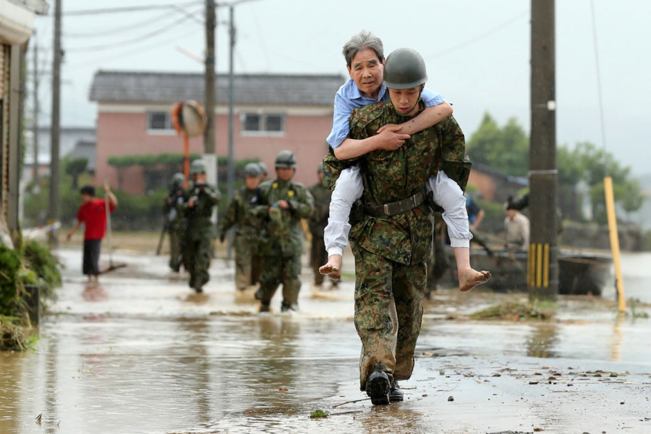 Japanese soldiers help local residents evacuate from floods in Fukuoka on Thursday.