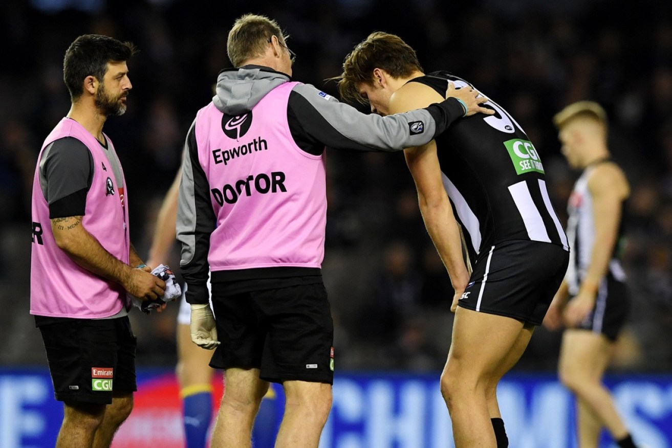 Collingwood's Darcy Moore is assessed by medical staff.