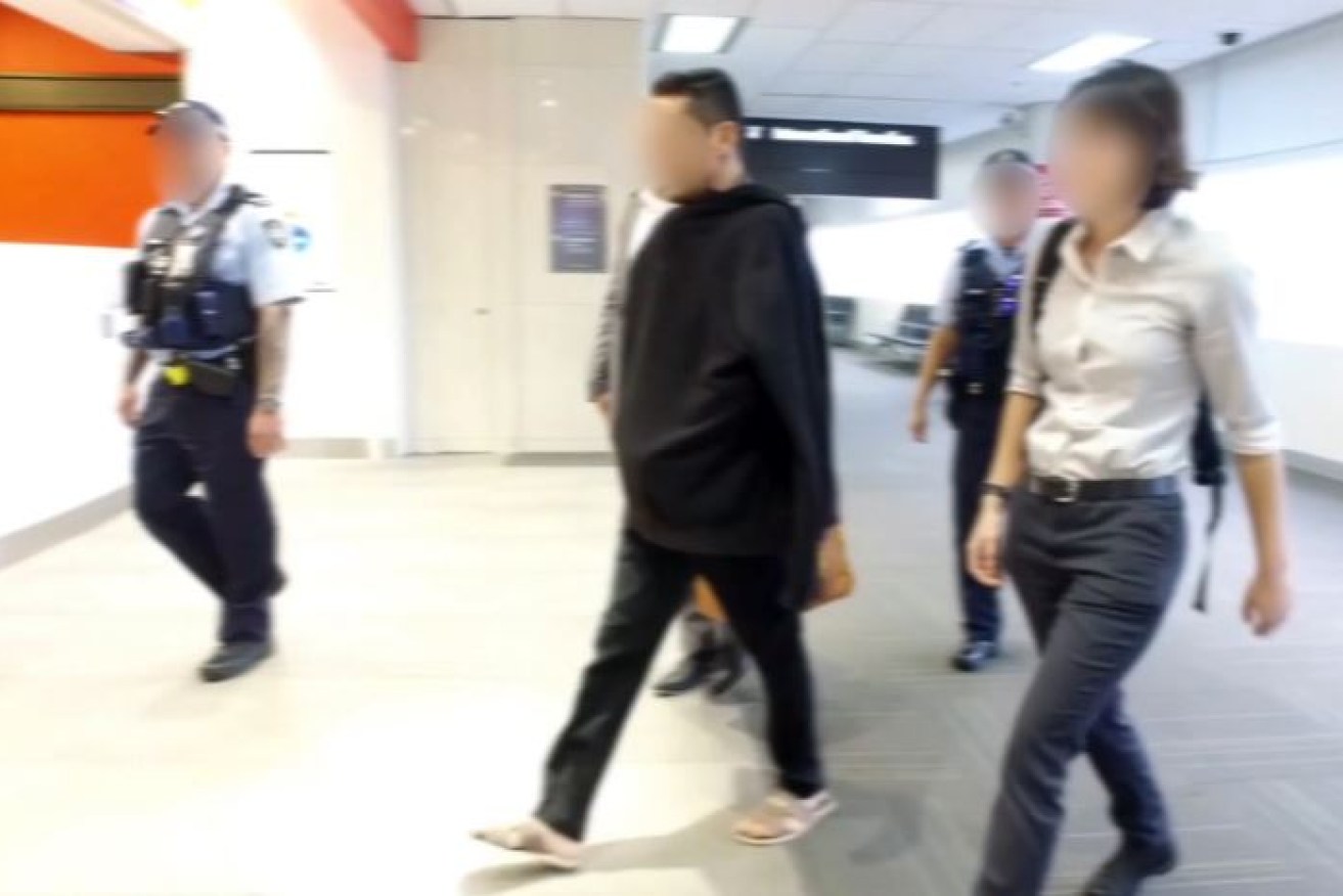 Accused people smuggler Ahmad Zia Alizadah is escorted through Perth airport on his way to court.