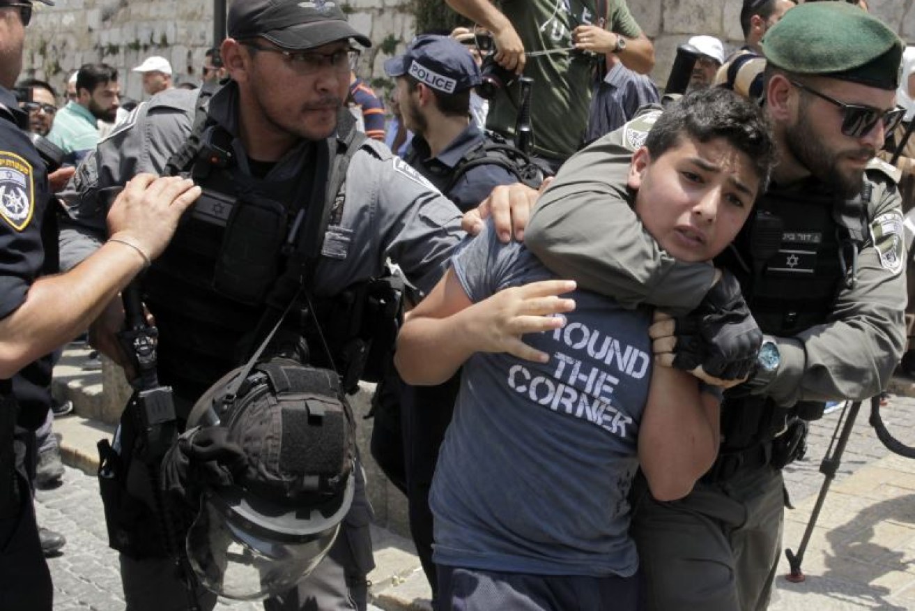 Israeli soldiers detain a teenage boy as tensions in Jerusalem escalate after a terror attack at Temple Mount.