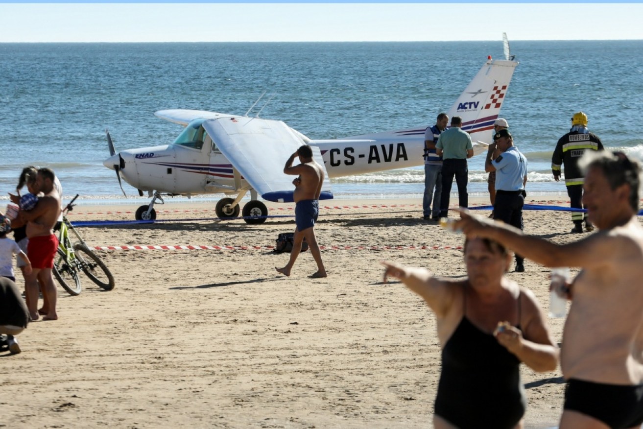 Two sunbathers died when a plane made an emergency landing on a popular beach.