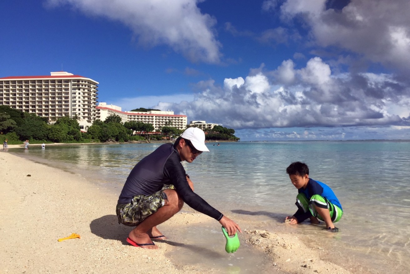 A Guamanian man playing on the beach with his son.