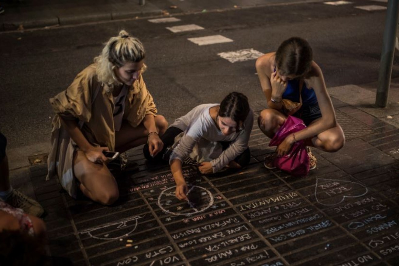 A girl draws a peace symbol on the street as a tribute to the victims of the Islamist attack in Barcelona.