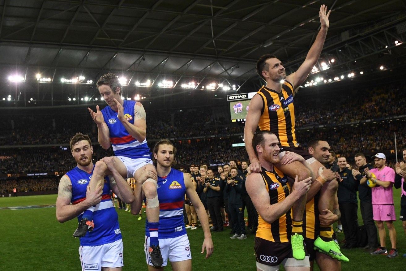 The two legends Bob Murphy and Luke Hodge salute the crowd as they're chaired off after playing their final AFL game. Photo: AAP 