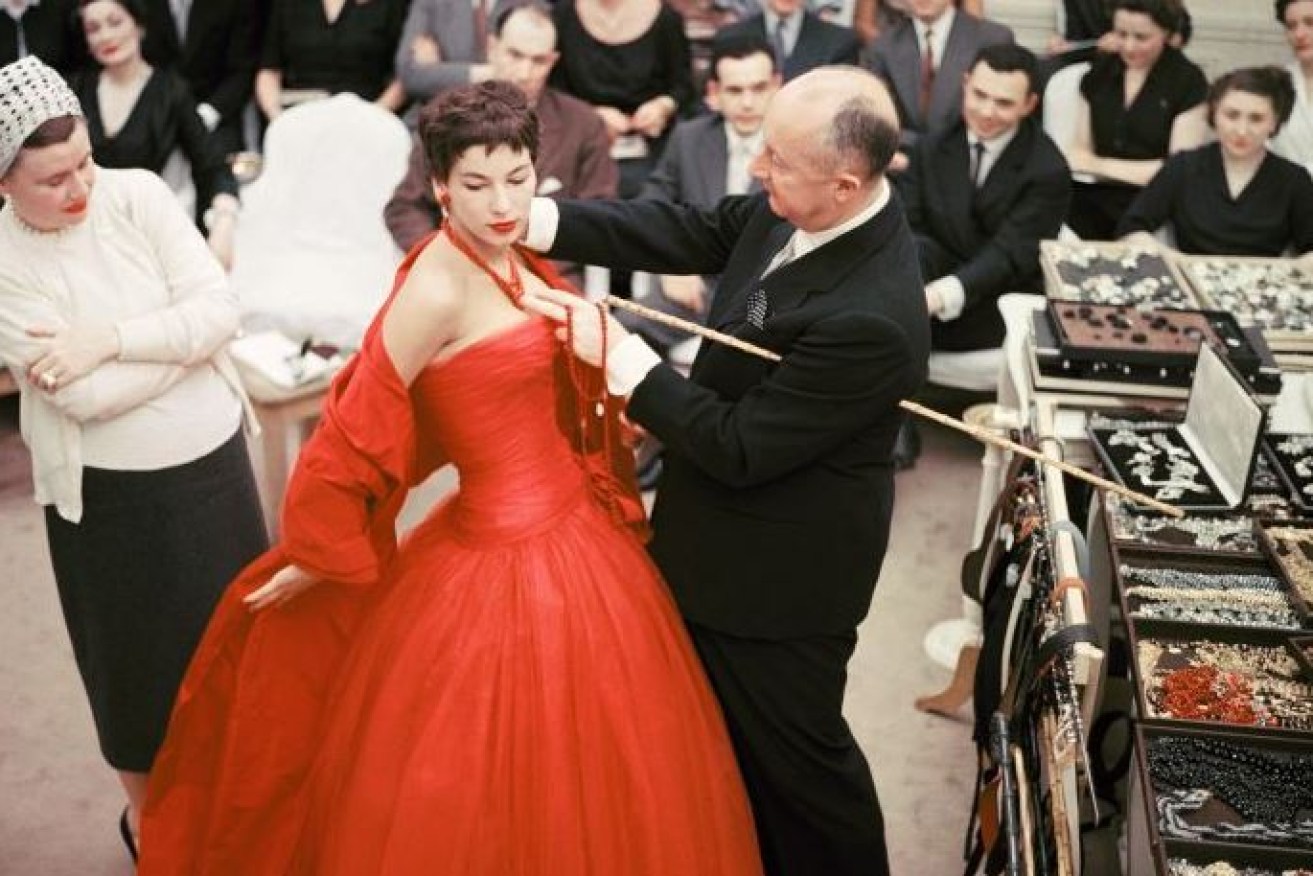 Christian Dior fine-tunes a catwalk model's accessories in 1954.