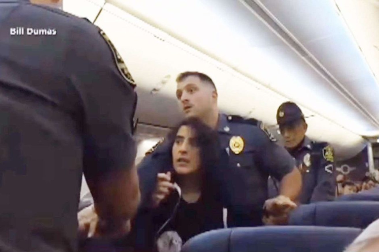 Police remove the woman as passengers wait to depart Baltimore airport.