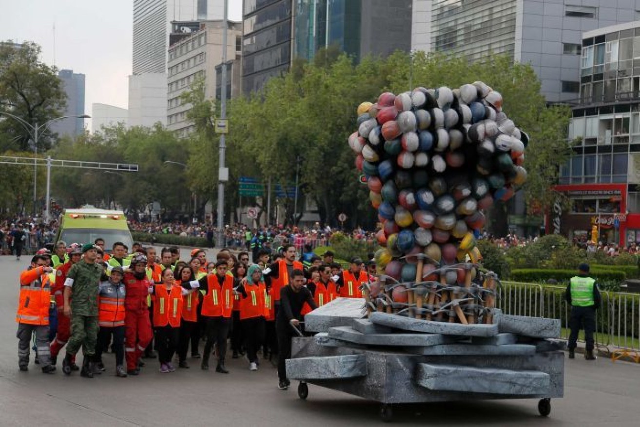 Rescue workers and volunteers march behind a fist made out of safety helmets. 
