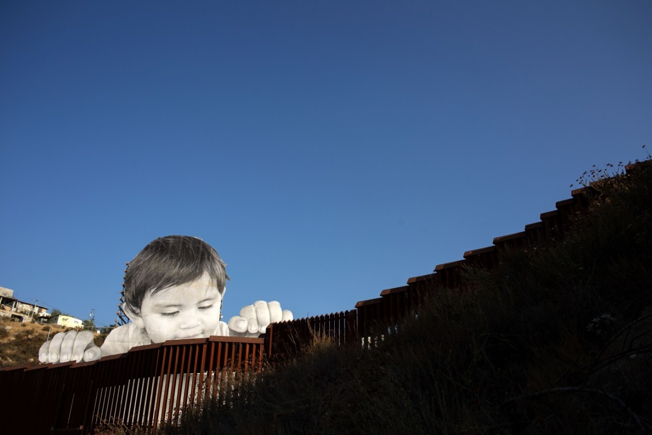 French artist JR's installation on the US-Mexican border shows a small boy peering across the divide.