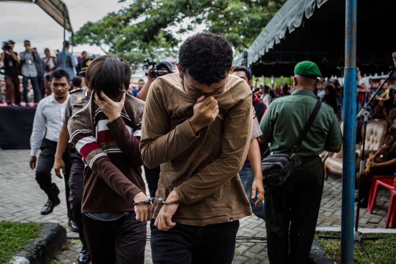 Two men arrive for caning for same-sex relations at a mosque in Aceh province of Indonesia.