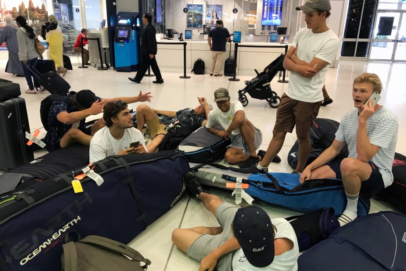 A group of surfers from Sydney wait for updates on their cancelled flight to Sumatra at Sydney Airport.