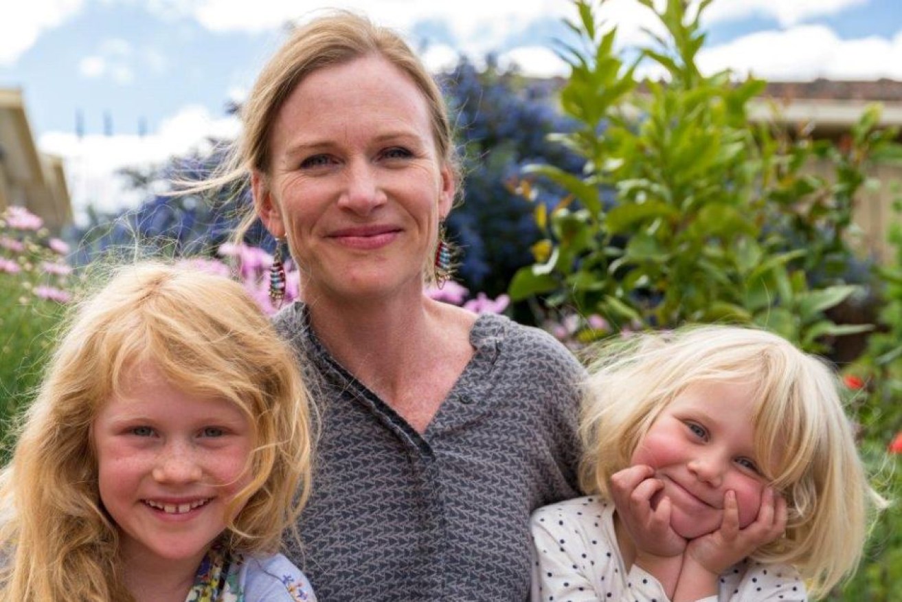 Meredith Wilson cuddles daughters Iris and Luca in her Hobart garden.