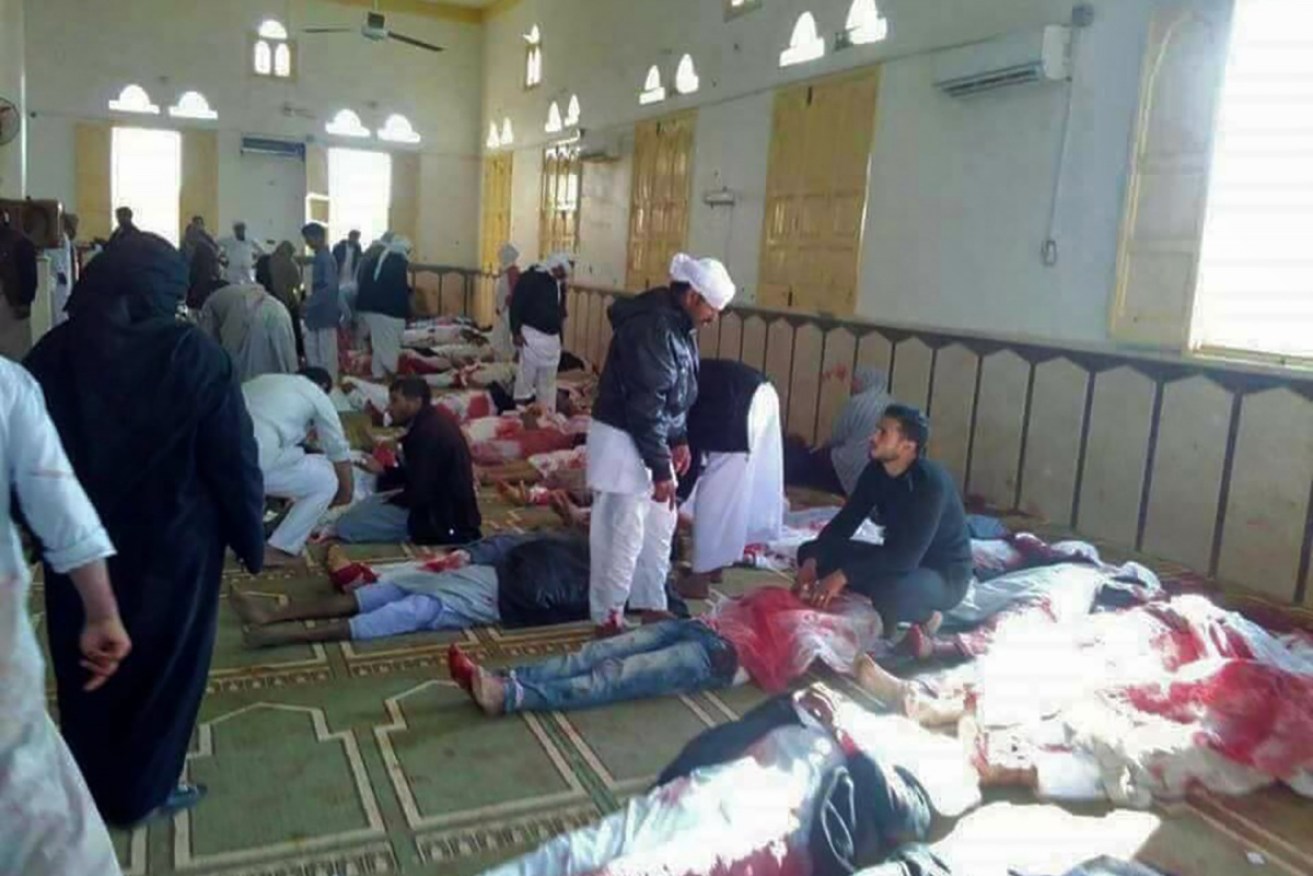 Egyptians walk past bodies following a gun and bombing terror attack at a mosque in Egypt.