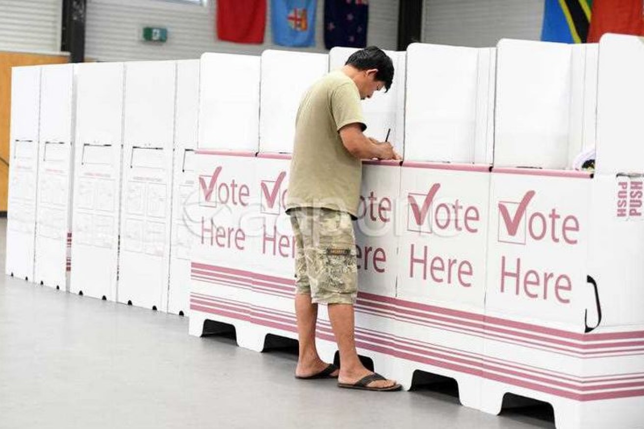 A Brisbane voter marks his ballot in an election marked by a regional divide and statewide disenchantment with major parties.