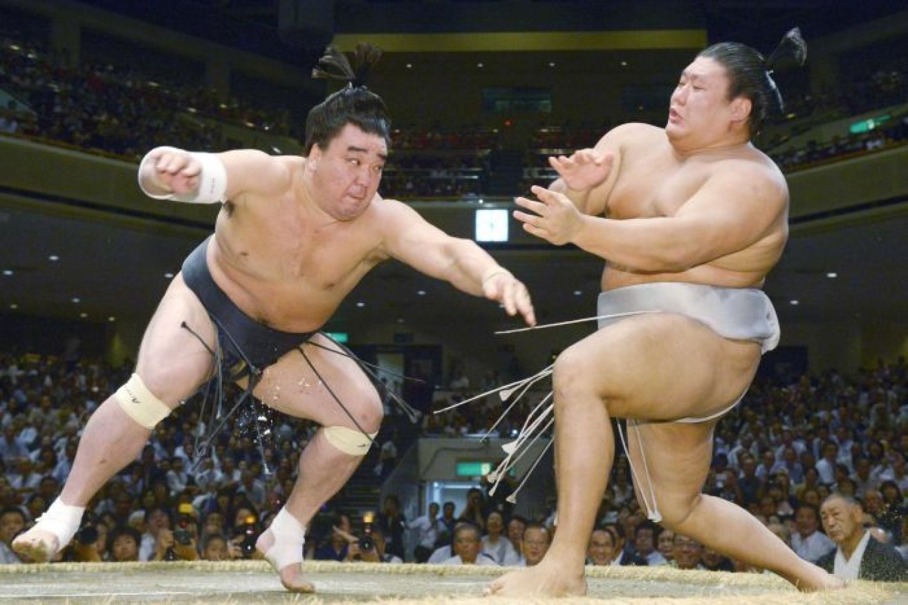 Harumafuji, left, pushes opponent Takanoiwa out of the ring to win their bout at the Autumn Grand Sumo Tournament in Tokyo.
