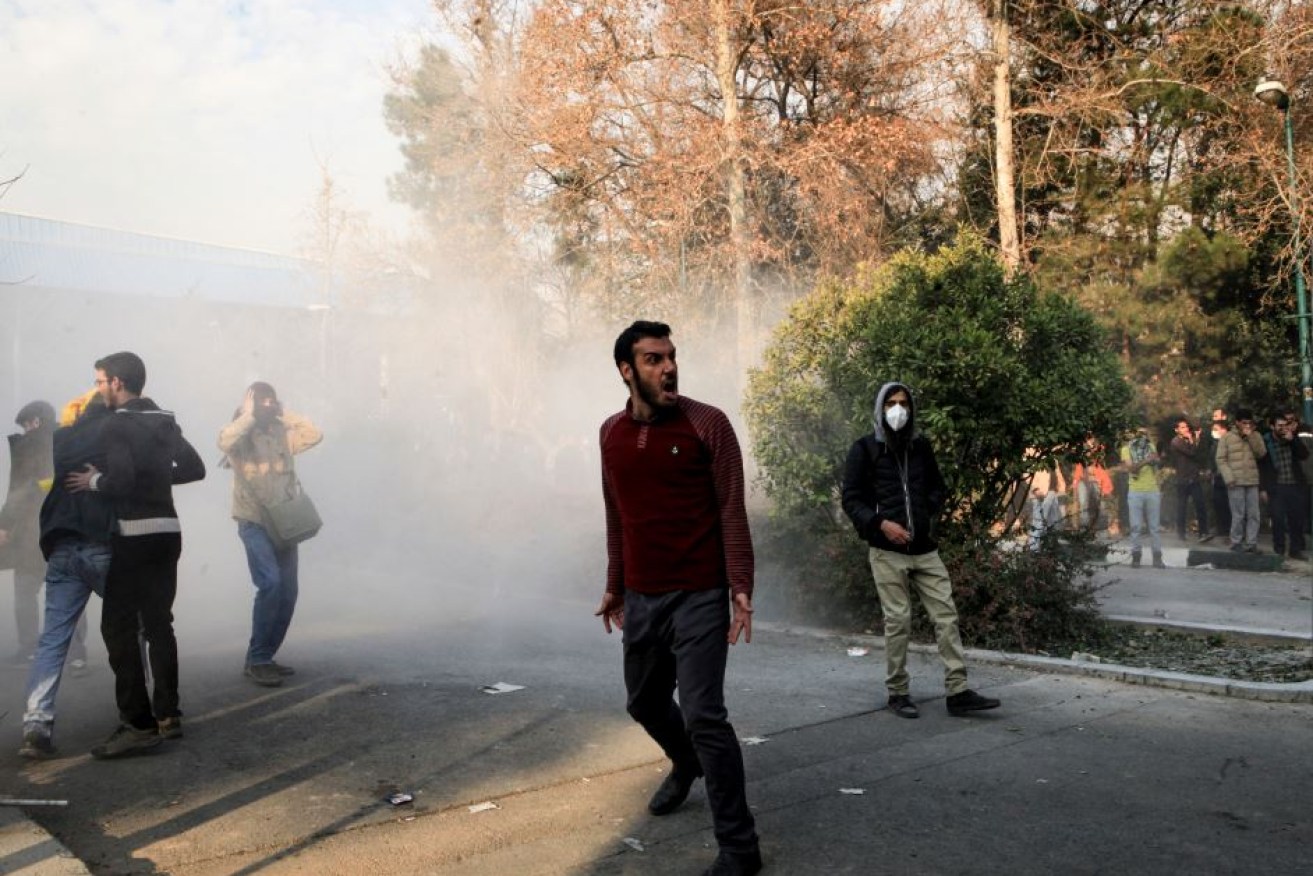 Emerging from a cloud of smoke and tear gas, a protester screams his defiance of the Tehran regime.