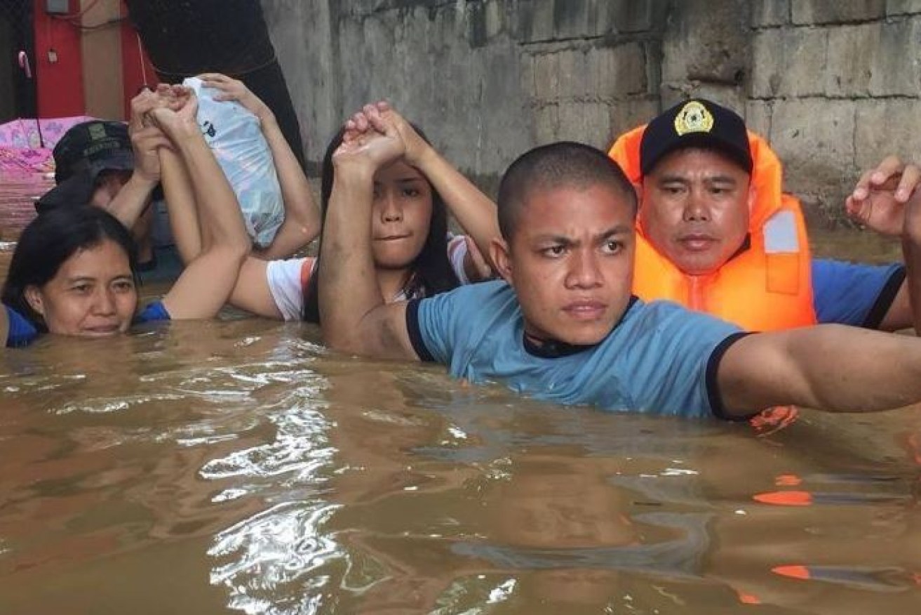 Chest-deep in floodwaters, southern Philippines residents inch their way through flood waters.