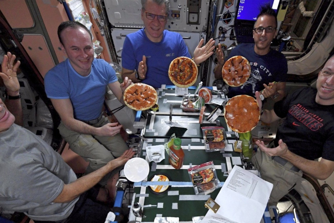 Astronauts display the results of their made-from-scratch pizza pies at the International Space Station. 