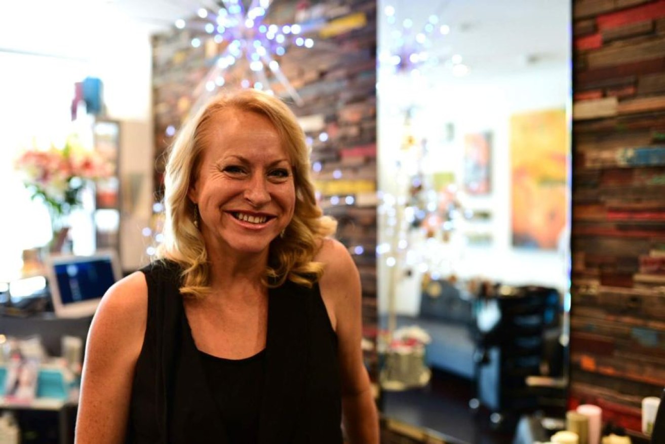 Veronica Ford, 46, smiles in her new workplace, a hair salon in Brisbane.