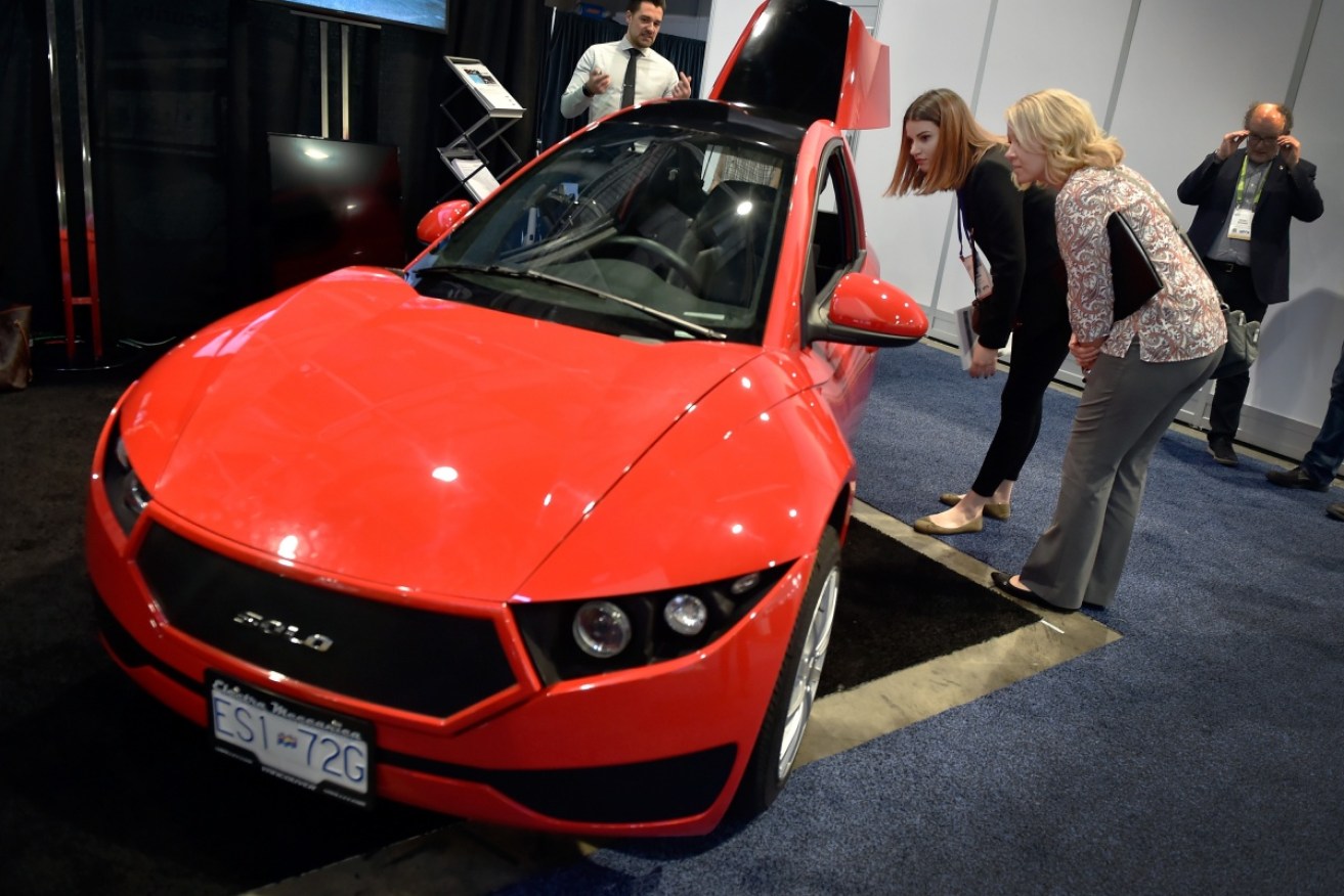 Attendees examine the Electra Meccanica Solo, an electric vehicle during CES 2018 in Las Vegas.